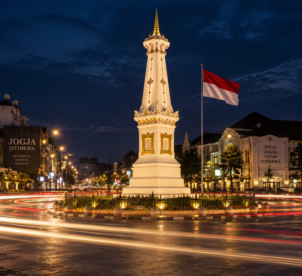 Tugu Pal Putih Yogyakarta diterangi lampu malam bersanding dengan bendera Merah Putih sebagai simbol keutuhan NKRI.